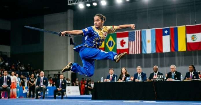 Atleta de alto rendimiento ejecutando una rutina de Taolu con espada en un torneo panamericano.