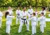 El “bajón” de verano: Estrategias clave para que tu escuela no se vacíe durante las vacaciones Clase de karate al aire libre integrada por padres e hijos durante las vacaciones de verano.